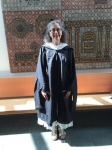 A woman wearing a graduation gown while smiling.