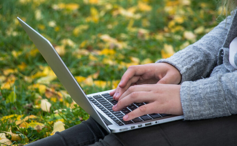 personon laptop sitting on grass