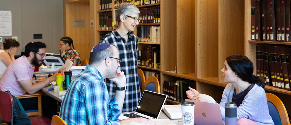 students and faculty member talking in beit midrash