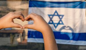 Israeli flag with hands making a heart in front of it